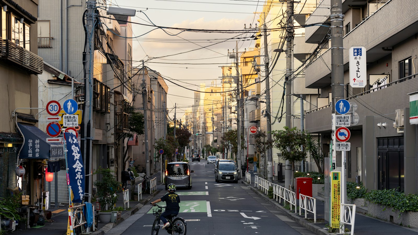 Tokyo'da dar bir mahalle sokağında bisiklet süren biri